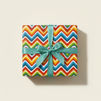 Square gift wrapped in rainbow chevron paper with a teal ribbon.