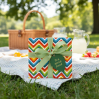 Colorful zigzag birthday gift wrap with green ribbon on picnic blanket.