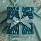 Teal gift wrapped in raindrop patterned paper with ribbon on matching draped fabric.