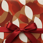 Close-up of a present wrapped in modern floral wrapping paper with a red satin bow.