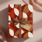 Modern gift box wrapped in abstract geometric wrapping paper with a brown ribbon and tag.