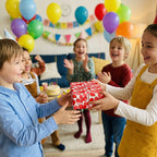 Kids exchanging a gift wrapped in white and red balloon birthday wrapping paper.