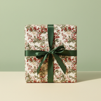 Elegant Christmas gift wrapped in botanical floral wrapping paper with a deep green ribbon.
