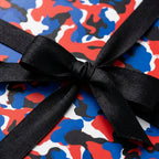 Red and blue camouflage wrapping paper with a black satin bow by Wrapped Studios.