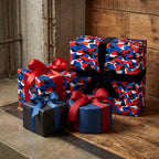 Red, blue, and white camouflage wrapping paper on gift boxes with bows by Wrapped Studios.