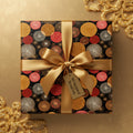 Elegant black wrapping paper with gold, red, and silver circle pattern and gold satin ribbon.