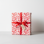 Romantic red heart pattern wrapping paper with a classic red satin ribbon and brown gift tag, perfect for Valentine's Day or anniversary gifts.