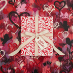 Red and white heart pattern wrapping paper with cream ribbon and "Joyful Moments" tag, ideal for Valentine's Day or anniversary gifts.