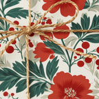 Close-up of floral wrapping paper with red blooms and a rustic twine bow, ideal for holiday or birthday gift wrap.