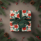 Elegant Christmas gift wrapped in floral paper with green ribbon, pine branches and berries.