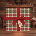 Square gift wrapped in red, green, and white plaid paper with a red ribbon, set in a cozy Christmas scene.