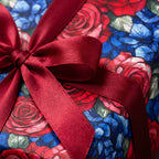 Burgundy ribbon on luxury floral wrapping paper with red and blue roses. Wrapped Studios.