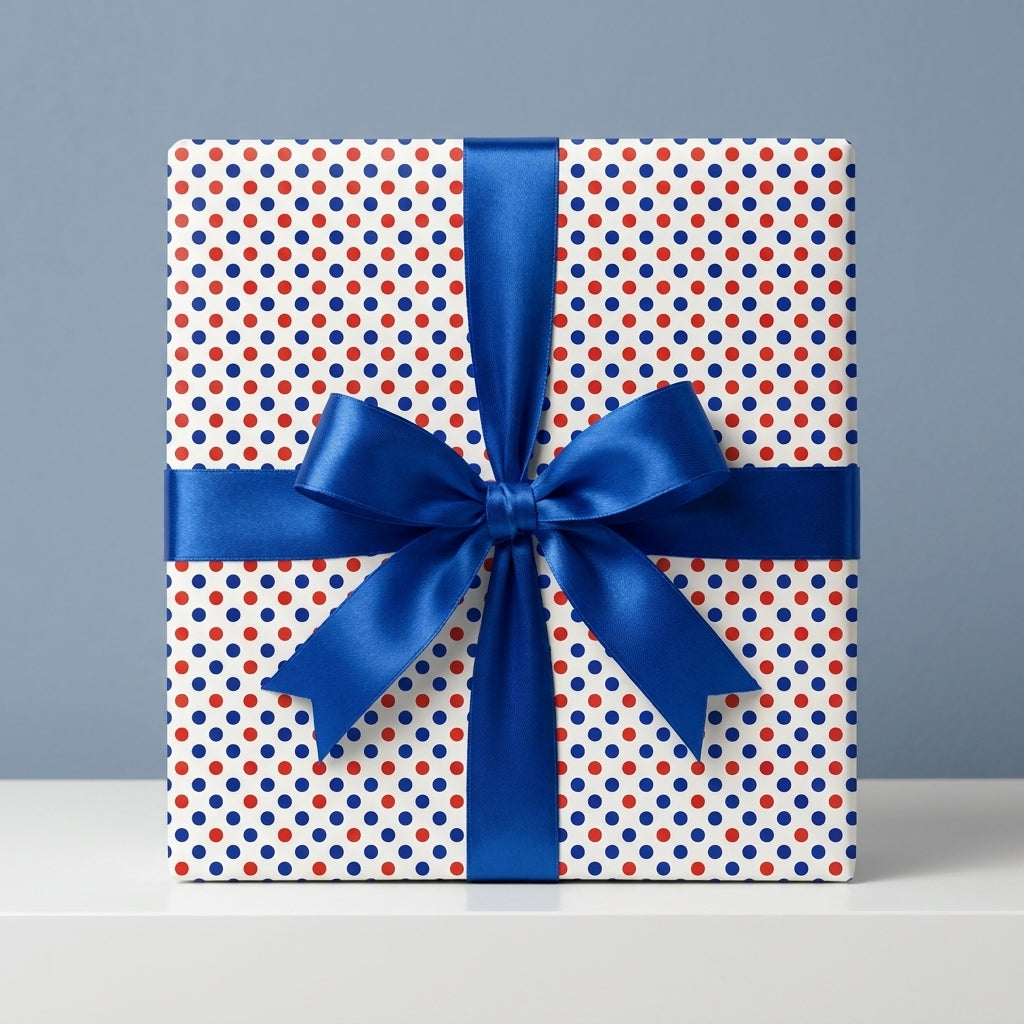Red and blue polka dot wrapping paper with a blue satin ribbon bow on a gift box by Wrapped Studios.