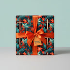 Square gift wrapped in floral wrapping paper with orange ribbon and bow on table.