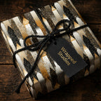 Elegant gift wrapped in black, gold and silver patterned wrapping paper with twine and black tag.