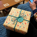 Cute bird birthday wrapping paper on a gift box with teal twine and 'Hi' tag by Wrapped Studios.