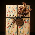 Mid-century modern bird gift wrap on a rustic package with wooden tag and black twine by Wrapped Studios.