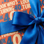 Look Who's Turning 40 birthday wrapping paper with a blue satin bow by Wrapped Studios.