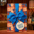 Retro 40th birthday wrapping paper with a blue ribbon and gift tag by Wrapped Studios.
