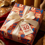 Red 40th birthday wrapping paper with a cream satin bow and "Cheers to 40 Years" tag by Wrapped Studios.