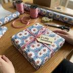 Vintage blue daisy floral wrapping paper with a pink ribbon on a gift box, by Wrapped Studios.