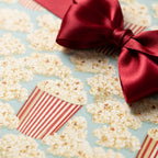Popcorn wrapping paper with a red satin bow, fun movie night gift wrap by Wrapped Studios.