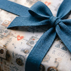 Retro robot wrapping paper with a textured blue ribbon bow, cute birthday gift wrap by Wrapped Studios.