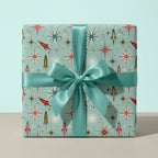 Retro space wrapping paper by Wrapped Studios with rockets and starbursts, tied with a teal satin bow.