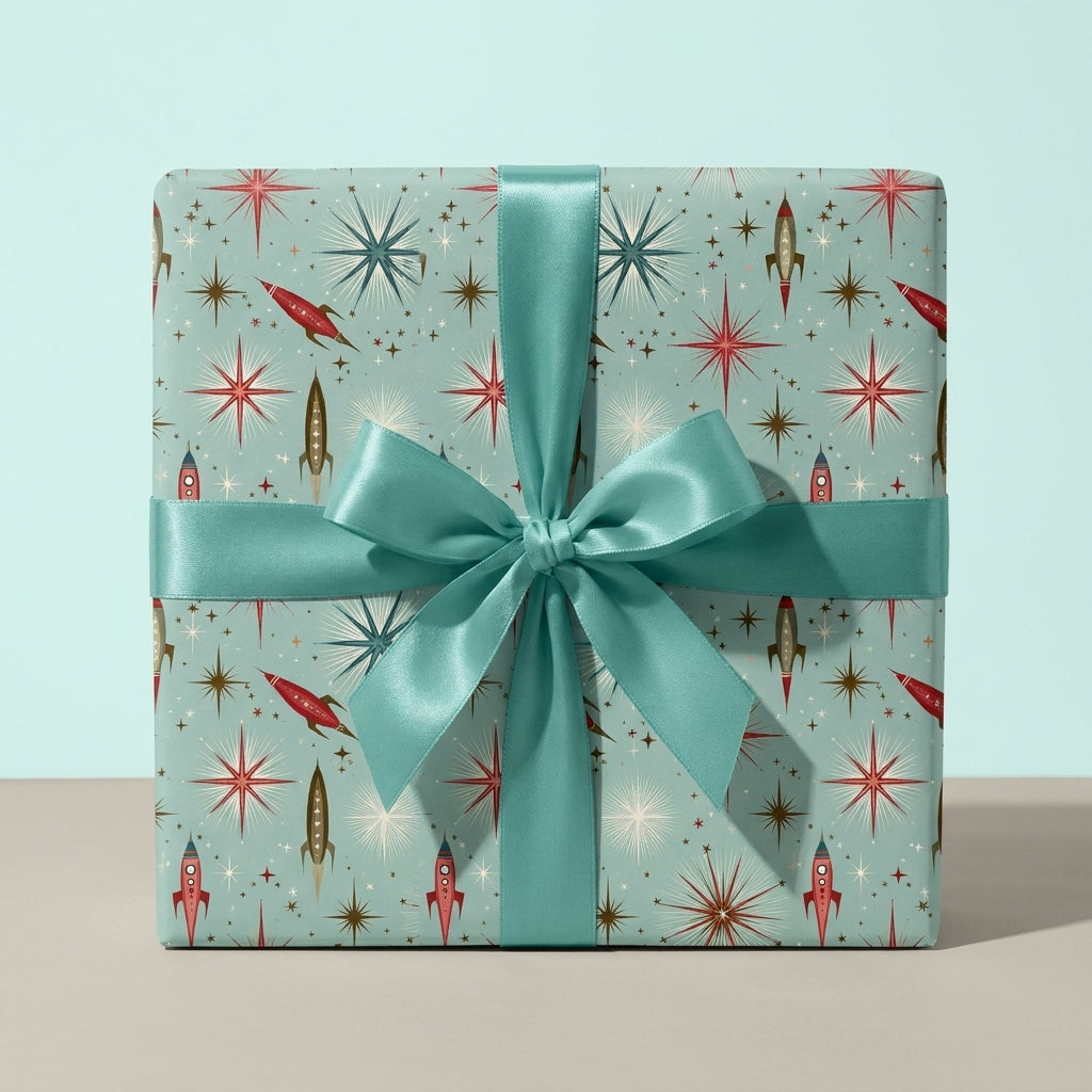 Retro space wrapping paper by Wrapped Studios with rockets and starbursts, tied with a teal satin bow.