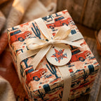 Western wrapping paper with red vintage trucks and cacti, tied with a cream bow by Wrapped Studios.