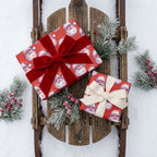 Vintage Santa Christmas wrapping paper by Wrapped Studios on gifts with bows on a wooden sled in snow.