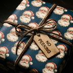 Vintage Santa Christmas wrapping paper in navy blue on a gift with a 'No Peeking' tag by Wrapped Studios.
