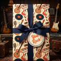 Retro music and guitar wrapping paper with a navy blue ribbon by Wrapped Studios.