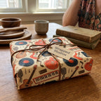 Retro music wrapping paper with guitars and vinyl records by Wrapped Studios on a gift tied with twine.