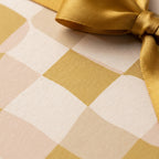 Textured gold and cream checkered wrapping paper with a luxurious gold satin bow.