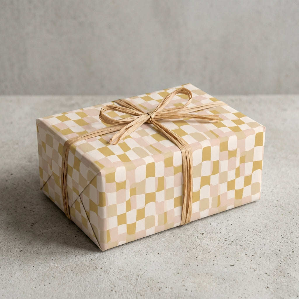 Modern wavy checkered wrapping paper in earth tones of mustard and pink, tied with a natural raffia bow.
