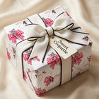 Coquette wrapping paper with red bows and luxury cream velvet ribbon on a gift box by Wrapped Studios.