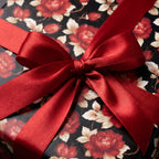 Luxury dark floral wrapping paper with a red satin bow on a gift box, by Wrapped Studios.