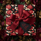 Luxury dark floral gift wrap by Wrapped Studios, featuring red roses, a burgundy ribbon bow, and a gift tag.