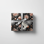 Luxury Christmas gift wrap with rose gold floral and silver ornament pattern, tied with a silver bow and gift tag.