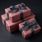 Elegant rose pink wrapping paper with gray ribbon bow on stacked gift boxes for birthday or wedding presents.