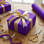 Square gift wrapped in purple paper with gold and silver ribbon, on wood surface.