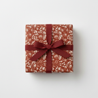 Square gift wrapped in floral wrapping paper with a burgundy ribbon and bow.