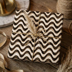 Boho neutral wavy wrapping paper tied with gold string and dried pampas grass by Wrapped Studios.