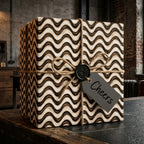 Modern black and cream wavy wrapping paper with rustic twine bow on a gift box by Wrapped Studios.
