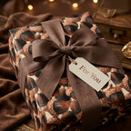 Rustic acorn wrapping paper with a brown linen bow and gift tag by Wrapped Studios.