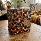 Rustic acorn wrapping paper by Wrapped Studios on a fall gift box tied with a thin bronze ribbon.