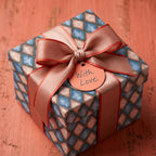 Luxury geometric wrapping paper on a gift box with a pink ribbon and 'With Love' tag by Wrapped Studios.