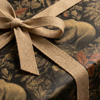 Rustic gift wrapped in forest animal wrapping paper with a neutral herringbone ribbon bow.