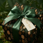 Woodland Christmas wrapping paper with a green satin bow and gold foil gift tag by Wrapped Studios.